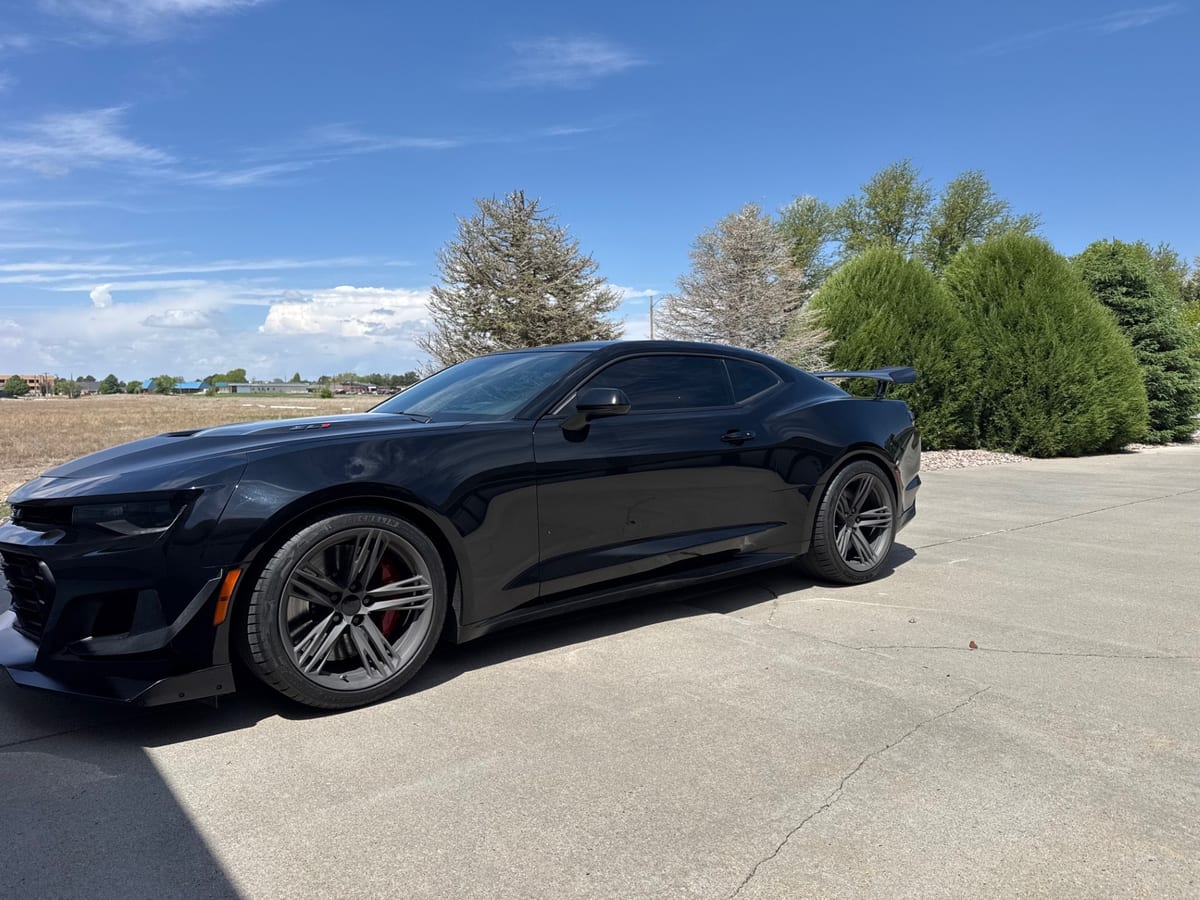 Black coupe with dark side windows parked outdoors.